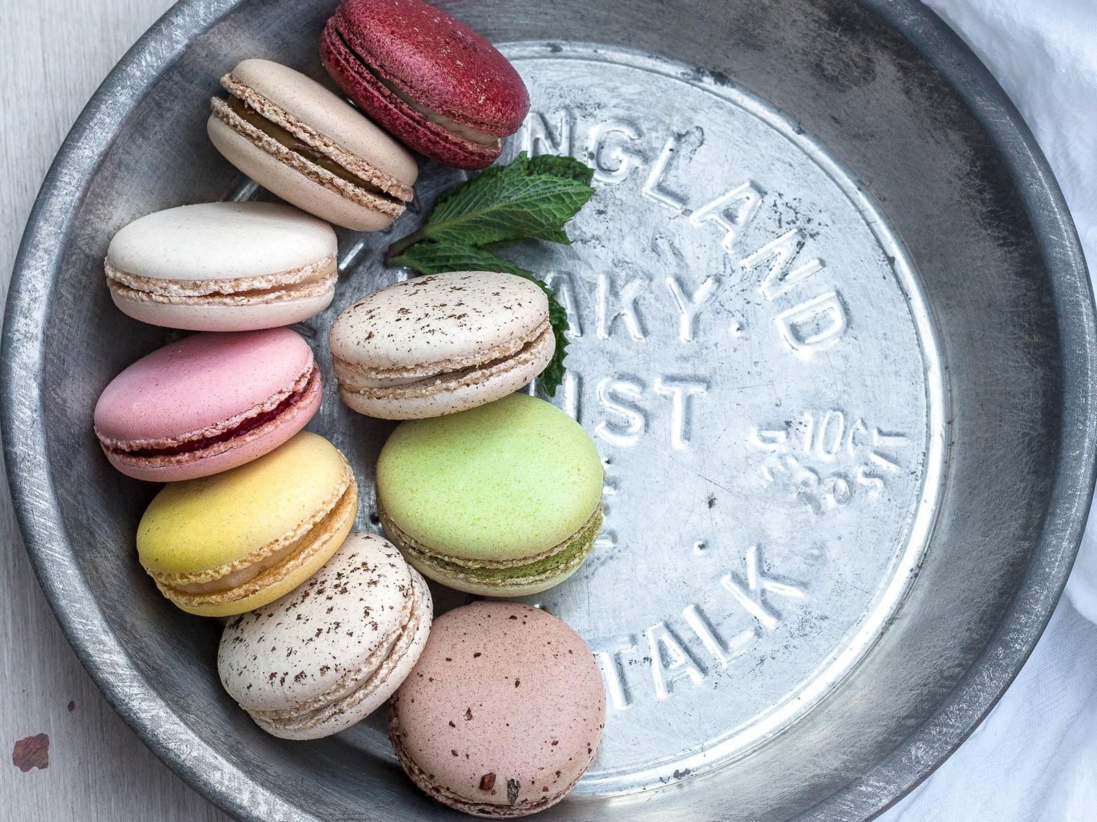 A variety of colorful French macarons served on a rustic metal tray, perfect for kitchen inspiration at our Einbauküchen Tessin studio.