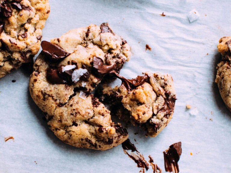 Freshly baked chocolate chip cookies with sea salt on parchment paper, perfect for enjoying in your dream kitchen from Einbauküchen Tessin.